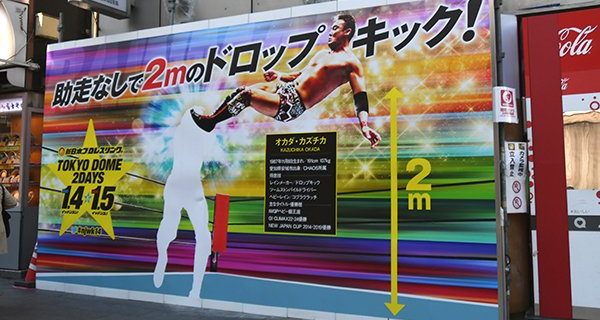 【新日本】東京・六本木交差点に『WRESTLE KINGDOM 14』特大看板が出現  オカダ・カズチカ選手のドロップキックパネルも登場！